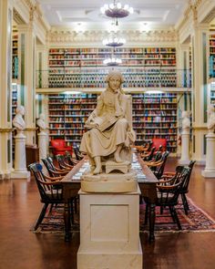 the library has many bookshelves and tables with chairs around it, along with a statue of abraham lincoln