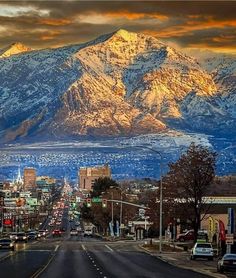 the mountains are covered in snow as cars drive down an empty street with buildings on both sides