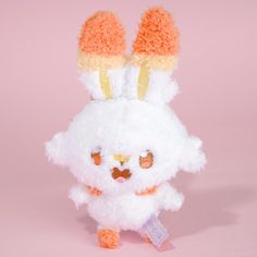 a white stuffed animal with orange and yellow ears