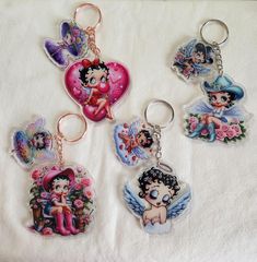 four keychains with cartoon characters on them sitting on a white cloth covered surface