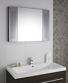 a bathroom with a sink, mirror and tiled wall behind the shower stall is seen in this image