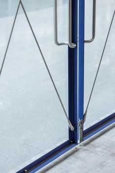 an open glass door on the side of a building with metal handles and bars attached to it