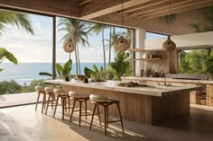 a large kitchen with an island counter and bar stools next to the window overlooking the ocean