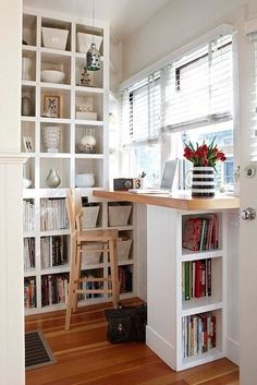 a home office with bookshelves and a desk in front of a window filled with flowers