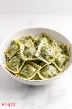 a white bowl filled with ravioli covered in pesto