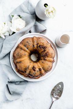 a bundt cake sitting on top of a white plate next to a cup of coffee