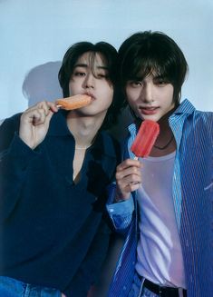 two young men are posing with popsicles in their hands