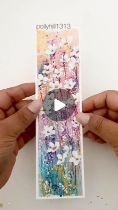 two hands holding up a card with flowers on it and the video is being displayed