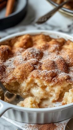 a close up of a casserole dish on a table with cinnamon sticks in the background