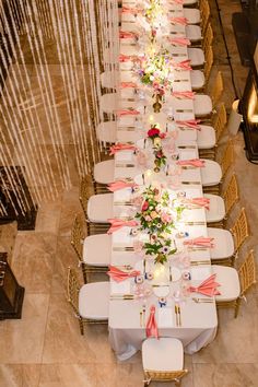 a long table is set up with white chairs and pink flowers on the tables for an event