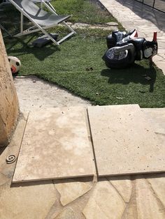 a motorcycle parked on top of a lush green field next to a stone patio area