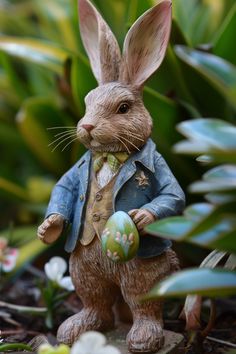 a rabbit figurine holding an easter egg in its hand and wearing a suit