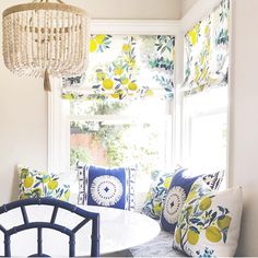 a white table with blue and yellow pillows next to a chandelier hanging from the ceiling