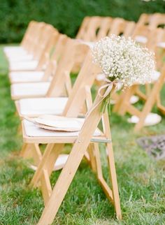 a row of wooden chairs with baby's breath flowers on them