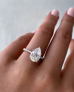 a woman's hand with a diamond ring on top of her finger and an engagement band