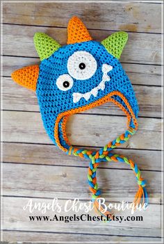 a crocheted blue monster hat with an orange nose and green horns on it