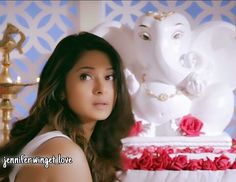 a woman standing in front of a cake with an elephant on it