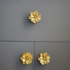 two gold flowers are placed on the side of a gray wall, and one is in the shape of a flower