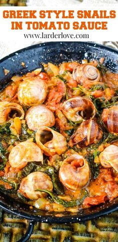 a skillet filled with shrimp and spinach in tomato sauce on top of a table