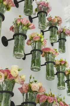 there are many vases with flowers in them hanging on the wall