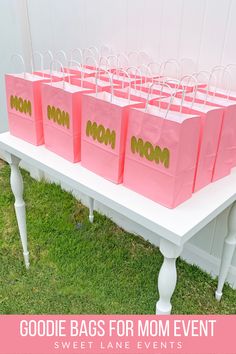 pink bags with gold mom's day messages on them sitting on a white bench