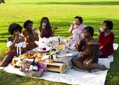 a group of women sitting on top of a grass covered field