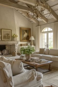 a living room filled with furniture and a chandelier hanging from the ceiling over a fire place