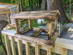 a wooden bird house sitting on top of a wooden deck next to a large tree