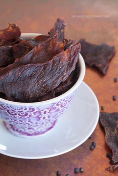 a cup filled with dried beef sitting on top of a plate next to some beans