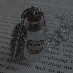 a bottle with a feather charm on it sitting on top of a page of paper