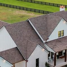 an aerial view of a white house with brown shingles and lights on the roof