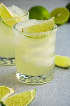 two glasses filled with lemonade and limes