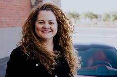 a woman standing in front of a red car