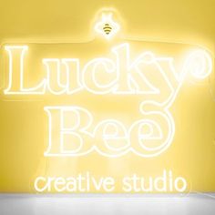 a neon sign that says lucky bee creative studio