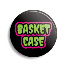 a black button with neon green and pink lettering that says basket case on the front