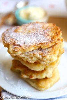 three pancakes stacked on top of each other on a white plate with powdered sugar