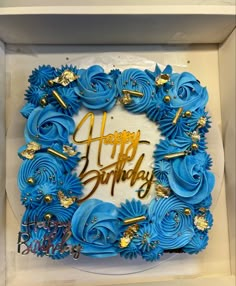 a birthday cake in a box with blue frosting and gold decorations on it that says happy birthday