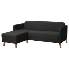 a black couch sitting on top of a white floor next to a wooden leg chair