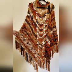 a crocheted shawl with tassels is hanging on a hanger