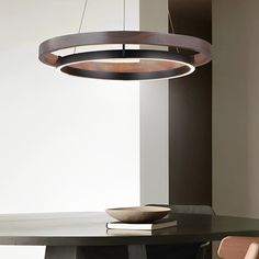 a round light hanging over a dining room table with two chairs and a bowl on it