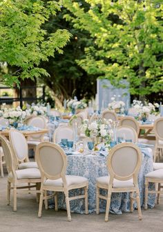 an outdoor dining area with blue and white table cloths, chairs, and tables