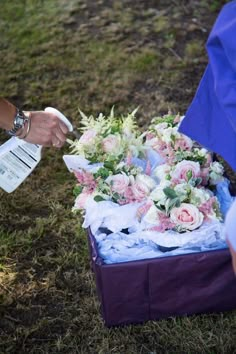 a person handing flowers from a box on the ground