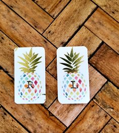 two cards with the letter i and a pineapple on them sitting on a wooden floor