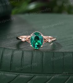 an oval green stone ring with diamonds on the band and side stones in rose gold