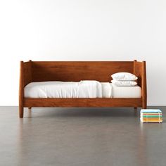 a bed with white sheets and pillows on top of it next to a stack of books