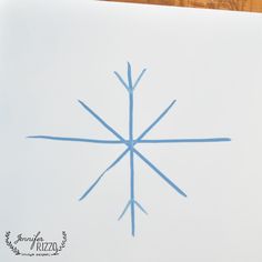 a snowflake is drawn on a piece of white paper with blue lines in the middle