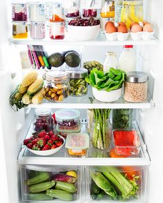 an open refrigerator filled with lots of different types of vegetables and fruits in containers on the shelves