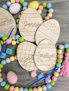 personalized wooden easter eggs on a table surrounded by candy and crochet beads