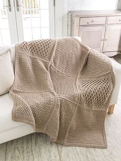 a living room with a white couch and a crocheted blanket on top of it