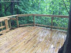 a wooden deck surrounded by trees in the woods